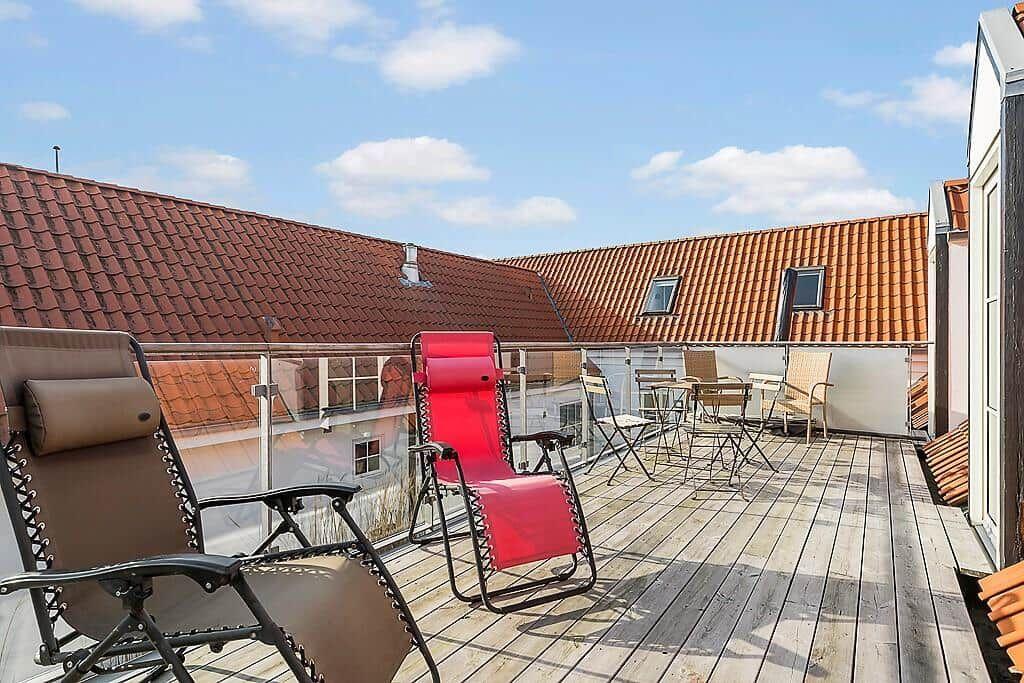 Terrace with loungers and table, view of red roofs.
