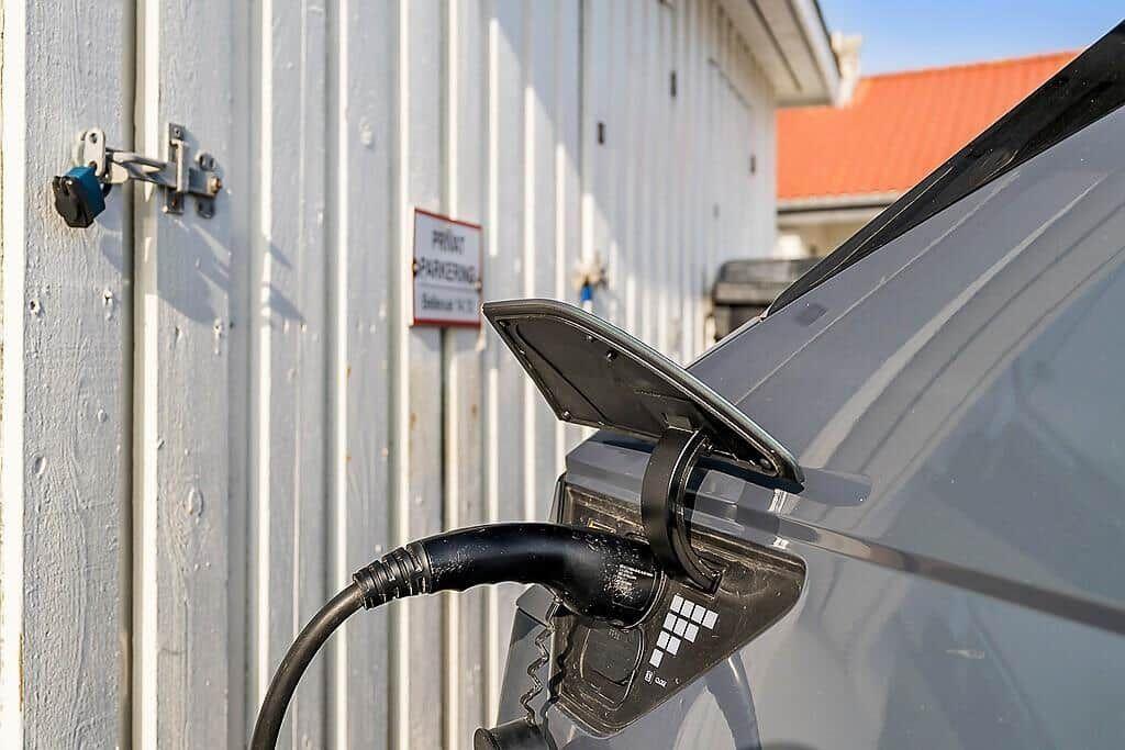 Electric car charging at wall socket. Sign indicates private parking.