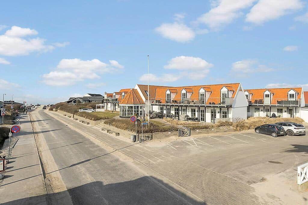 Row house with orange roof and balconies along the seaside road.