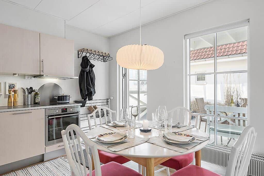 Kitchen and dining area with table, chairs, and window to terrace.