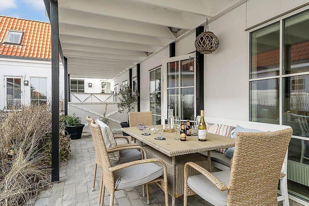 Patio with table, chairs, and drinks under cover.