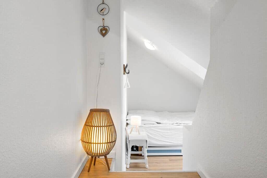 Bedroom with sloped ceiling, bed and standing lamp