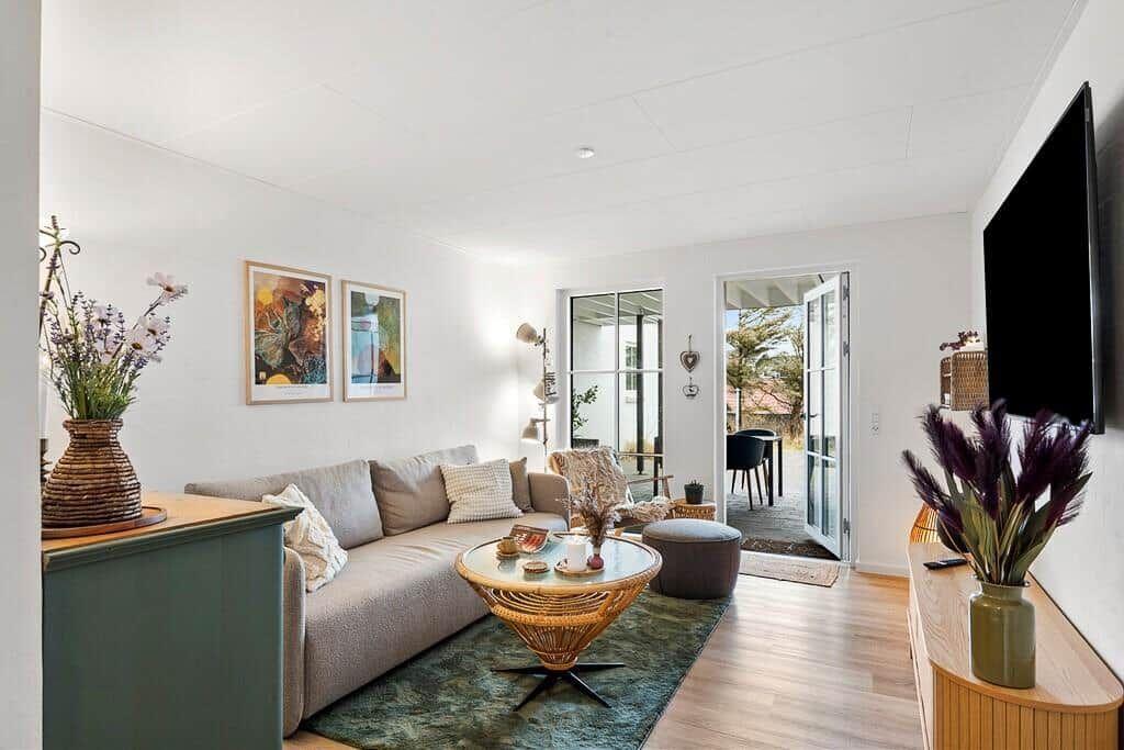 Living room with sofa, coffee table, and TV. Passage to terrace with tables.