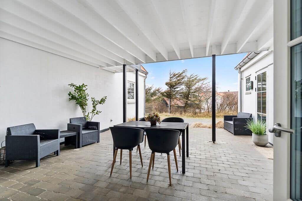 Terrace with seating group, table and chairs under white roof