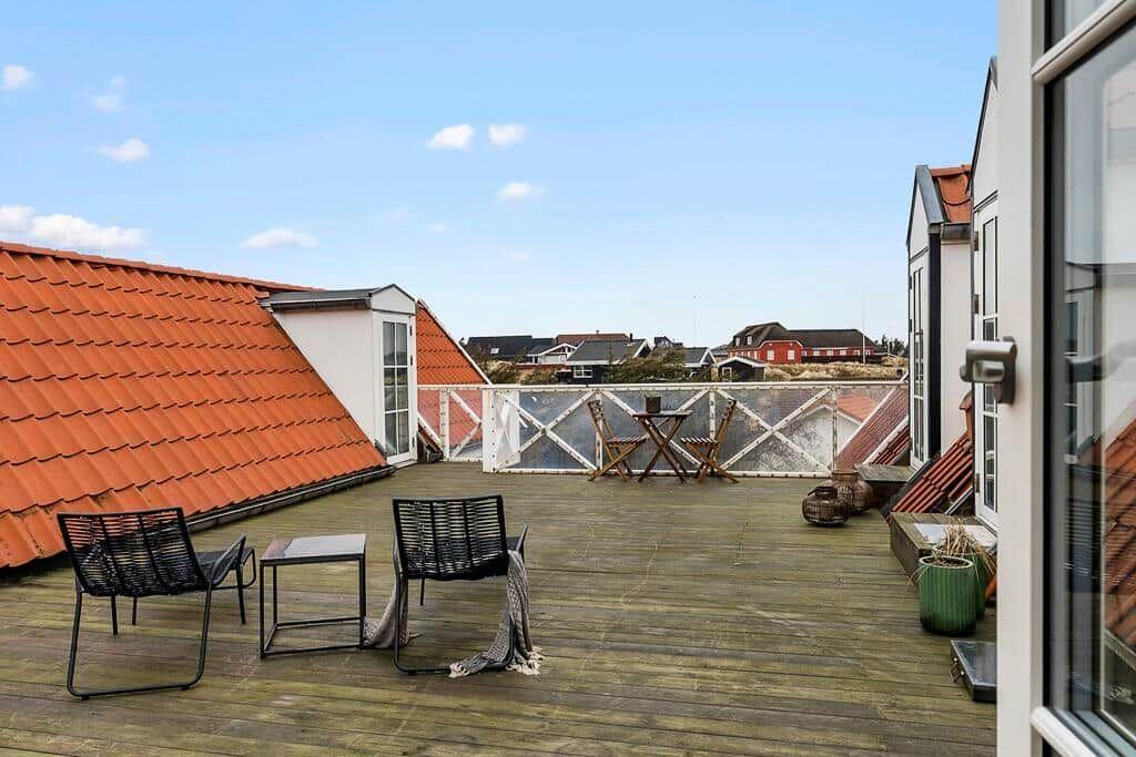 Terrace with two chairs, table, and view of rooftops.