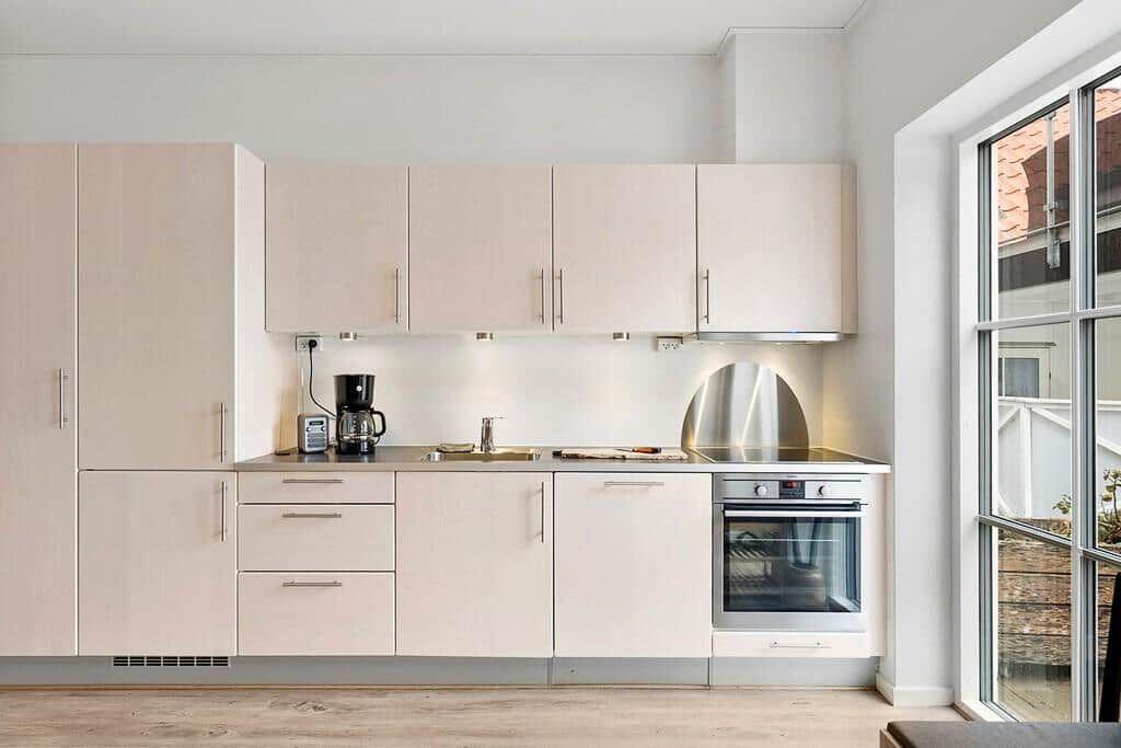 Modern kitchen with light cabinets, stainless steel appliances, and large window.