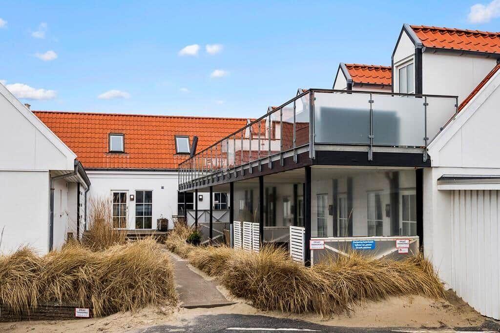 House with balcony and red roof, surrounded by dry grass.