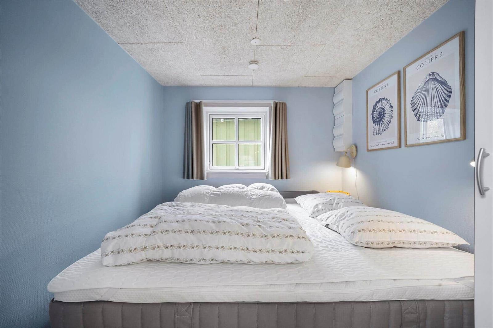 Schlafzimmer mit Bett, Fenster und Wandbildern