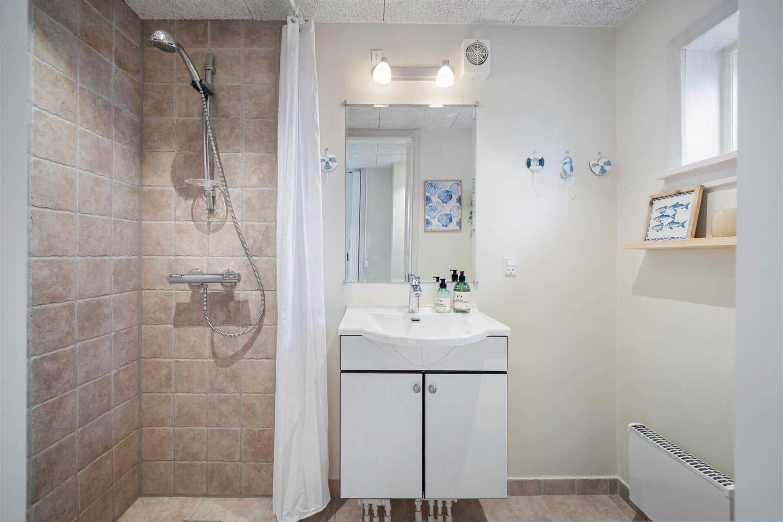 Badezimmer mit Dusche, Waschbecken und Spiegel.