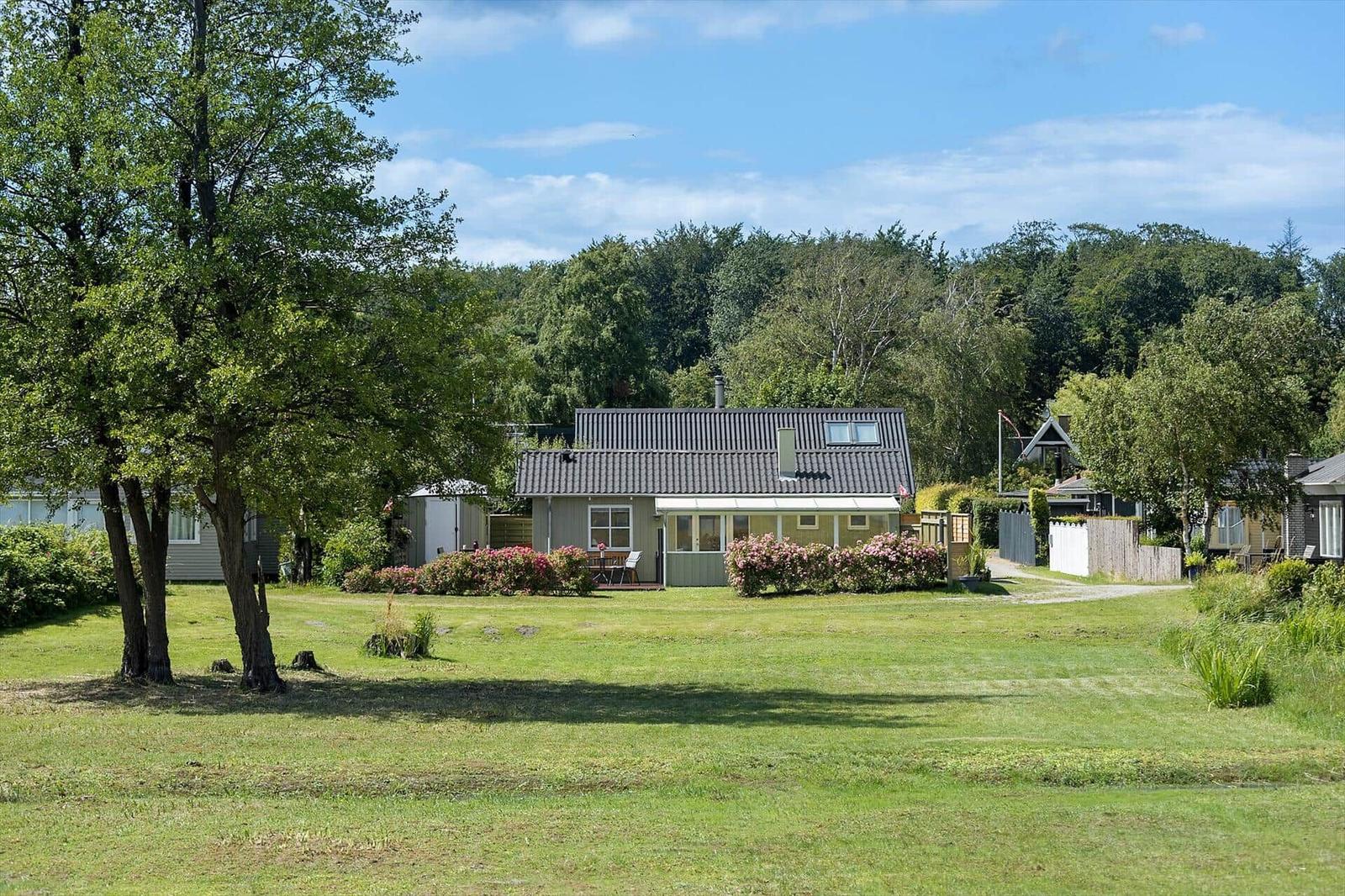Ein Haus mit Garten, Blumen und Bäumen unter blauem Himmel.