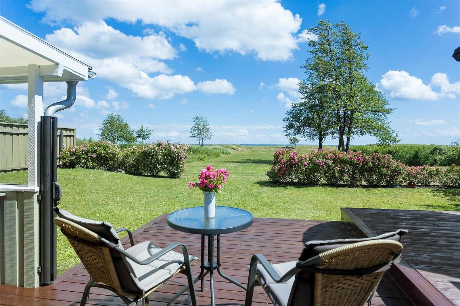 Terrasse mit Tisch und Stühlen, Blick auf grünen Garten und Horizont.