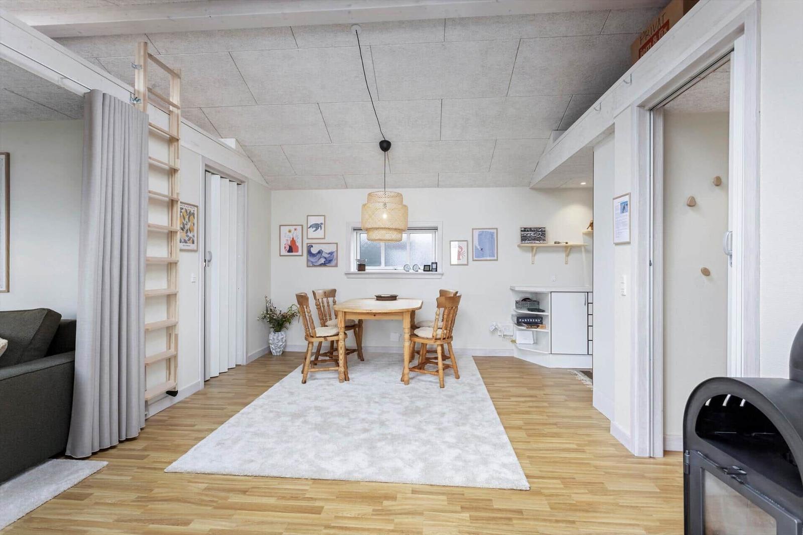 Essbereich mit Tisch, Stühlen und Deckenlampe. Holzfußboden und helle Wände.