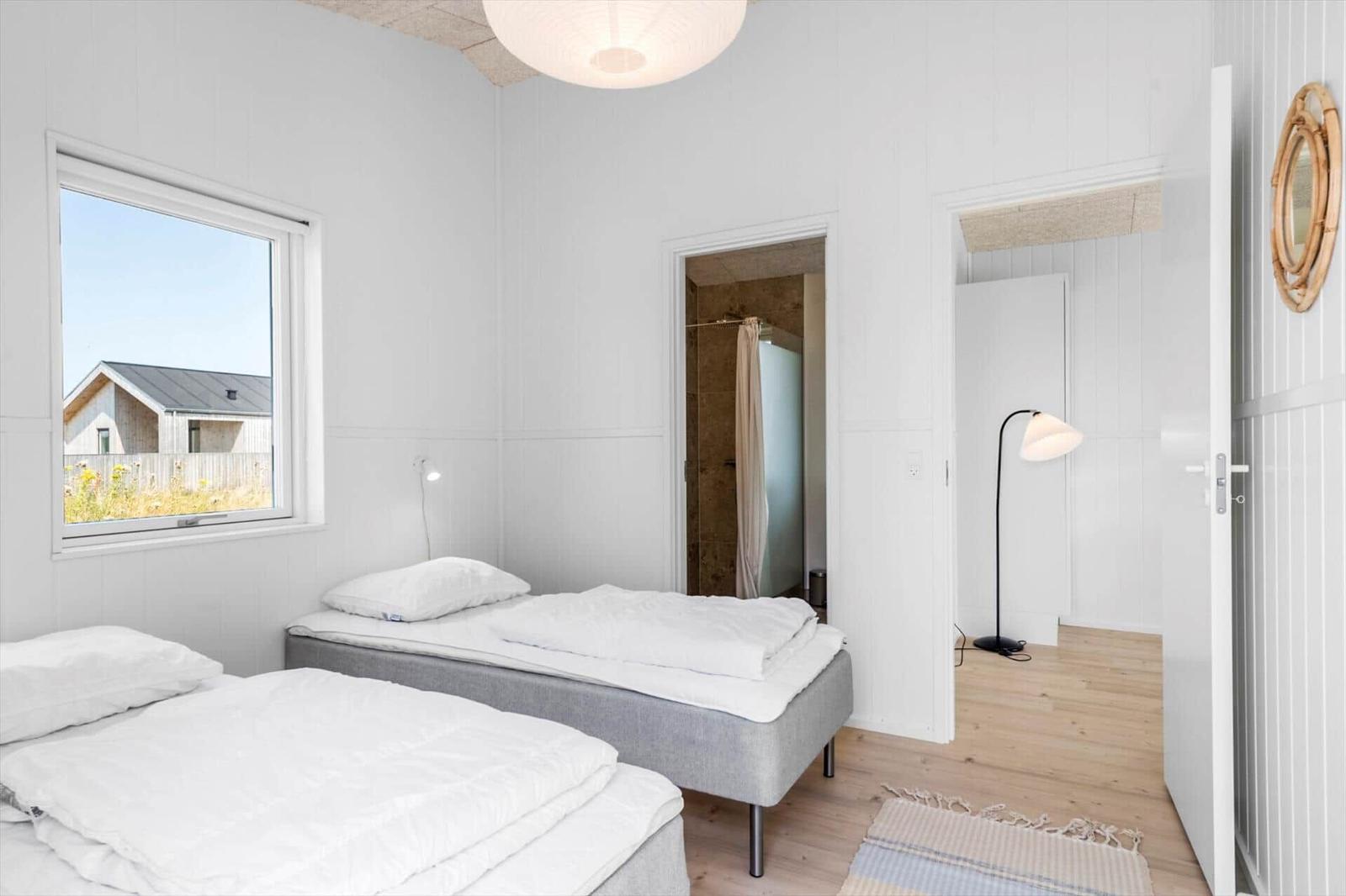 Zwei Betten, Fenster mit Aussicht, Badezimmer und Stehlampe.