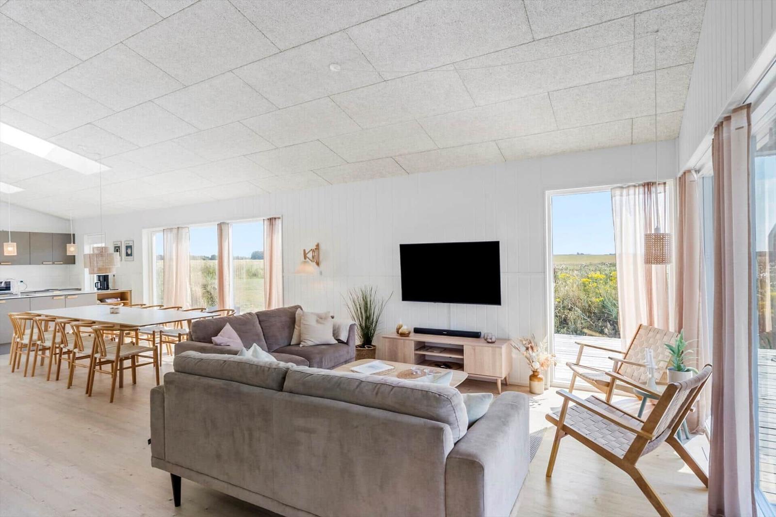 Wohn- und Essbereich mit Sofa, TV und Blick auf die Landschaft.