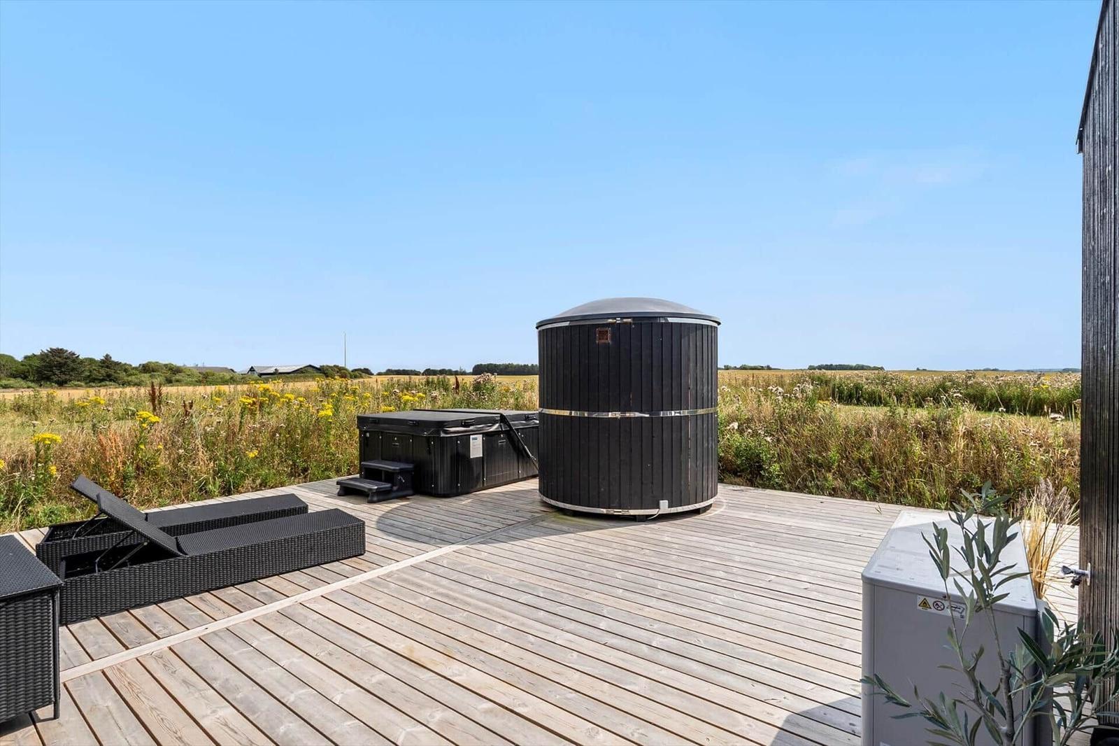 Holzterrasse mit Whirlpool und Liegestühlen im Freien.
