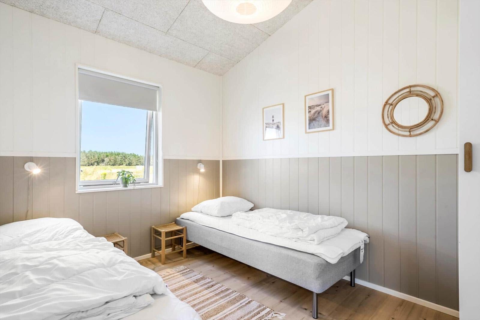 Schlafzimmer mit zwei Betten, Fenster und Wanddekoration.