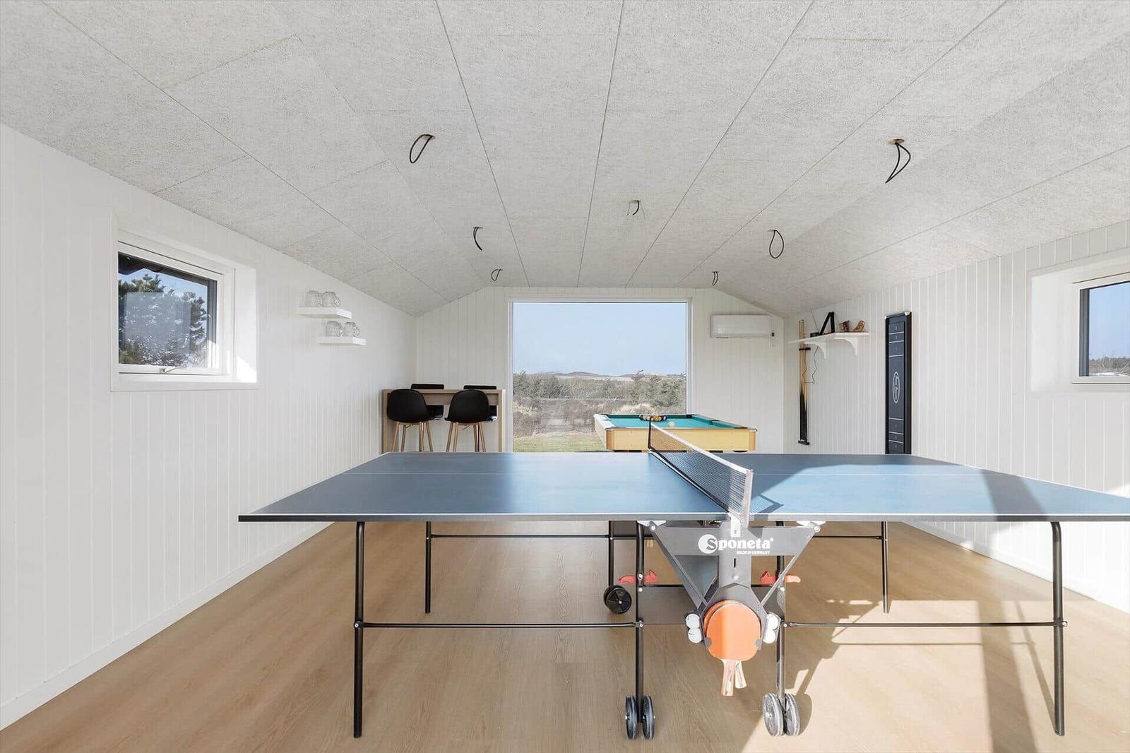 Room with ping pong table, pool table, and window with view.