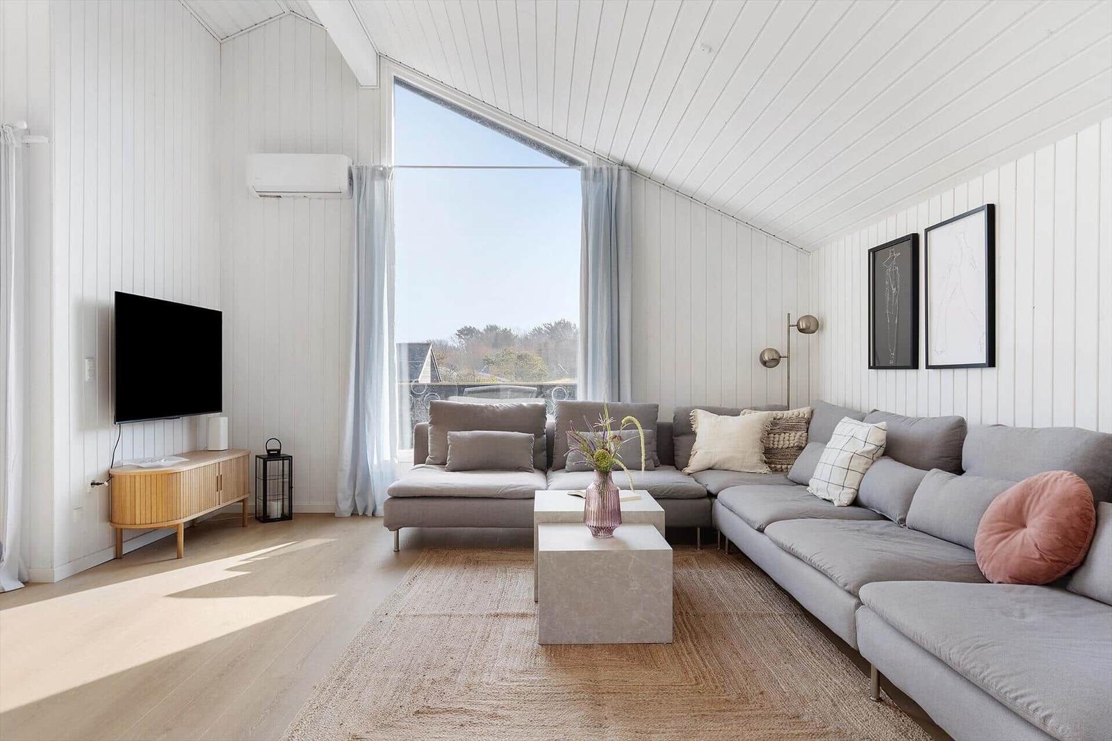 Living room with gray sofa, TV, and large window.