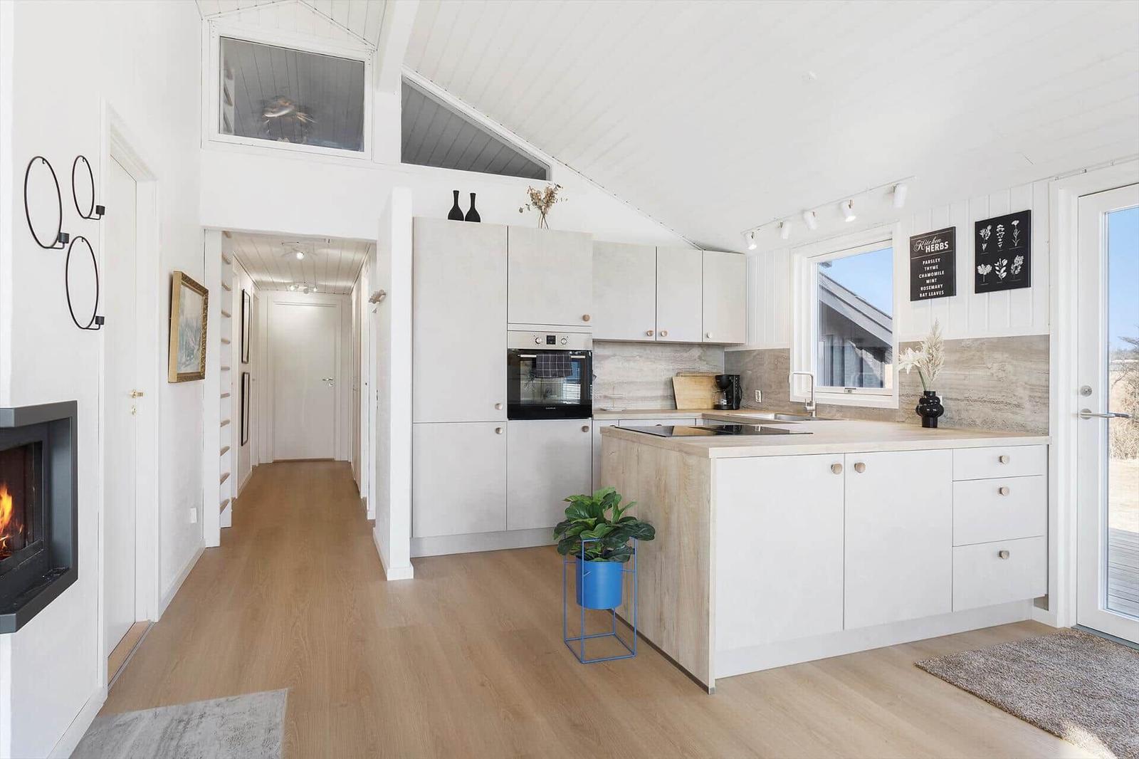 Kitchen with island, stove, and oven. Wooden floor and white walls.