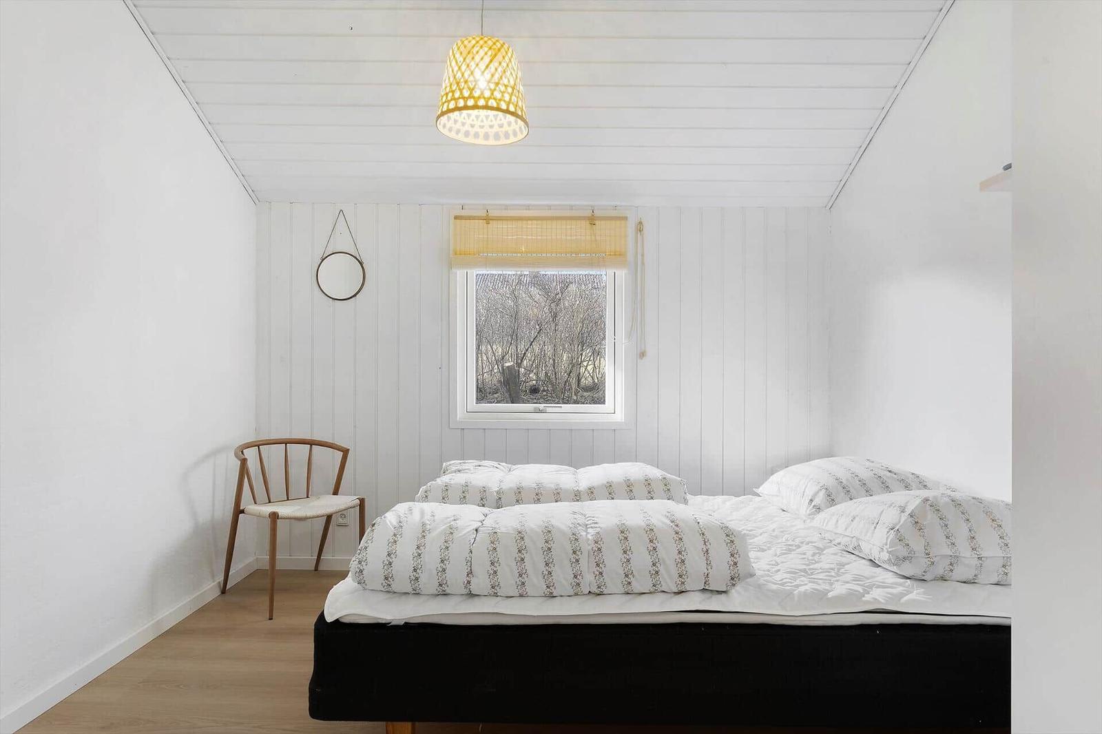 Bedroom with bed, chair, and window. Ceiling white, floor light brown.