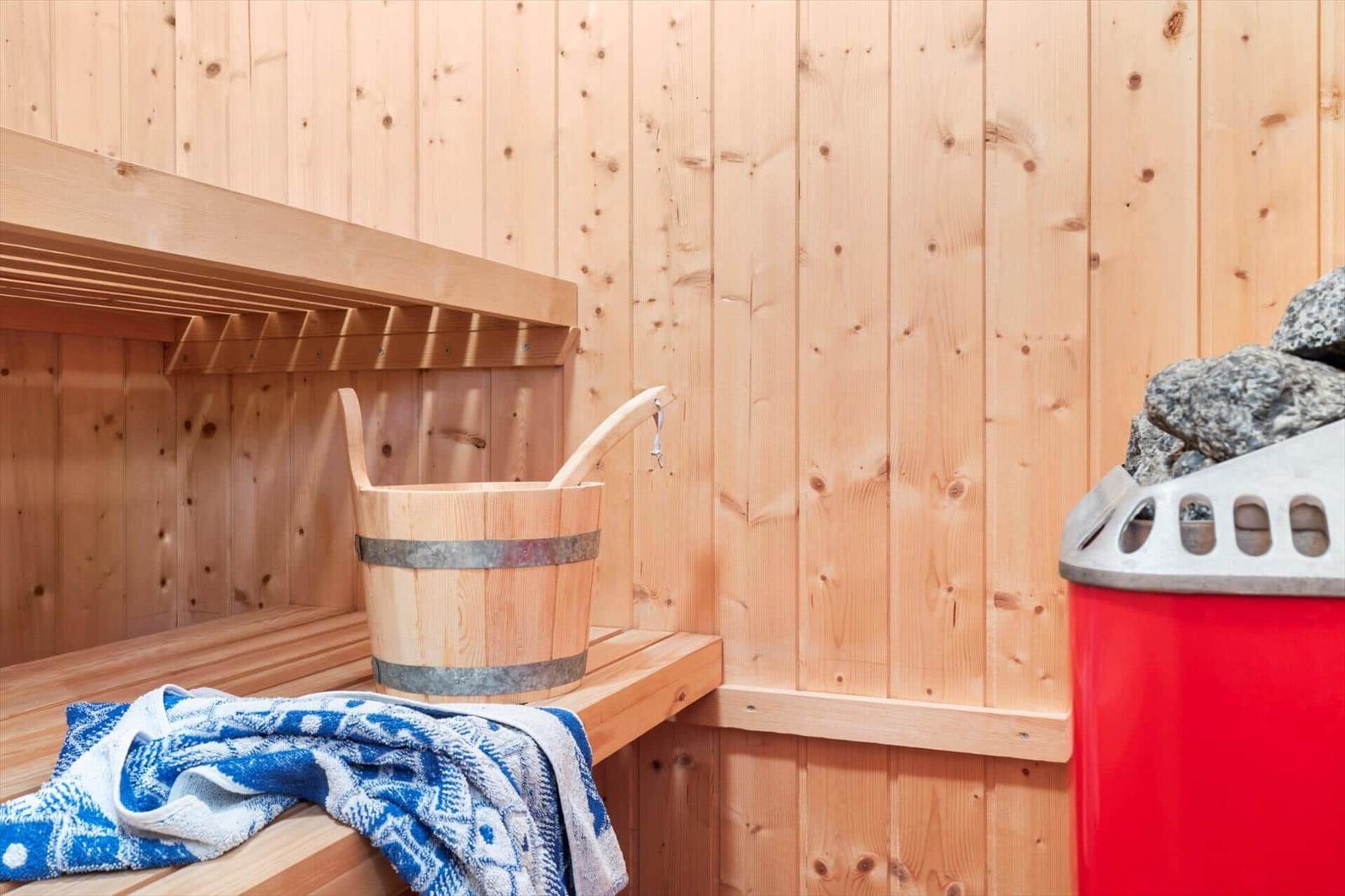 Sauna with wooden walls, bench, bucket, and towel.