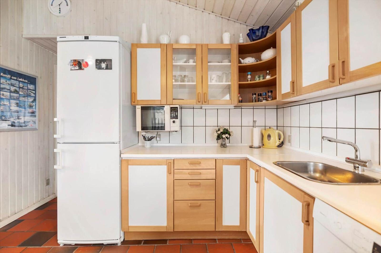 Kitchen with refrigerator, microwave, sink, and wooden cabinets.