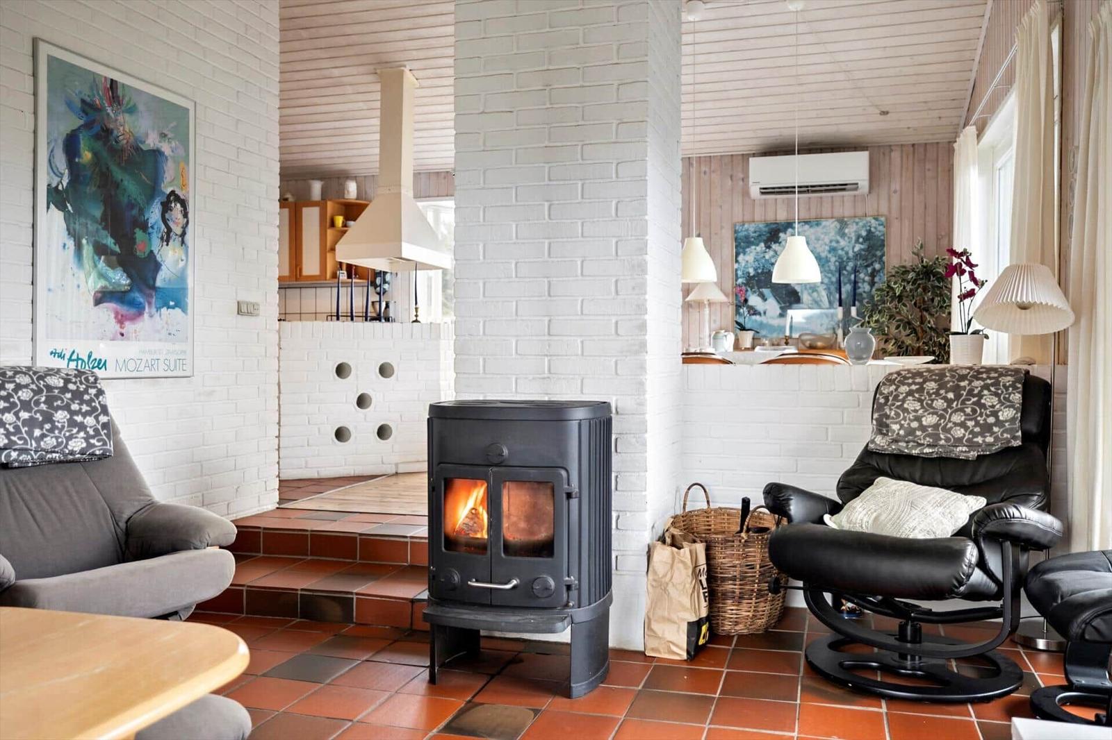 Living area with wood stove, seating, and kitchen area in the background.