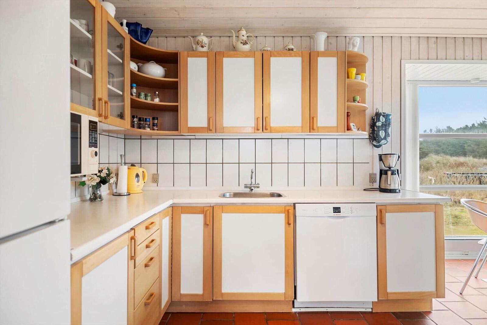 Kitchen with wooden cabinets, sink, and view of the outdoor terrace.