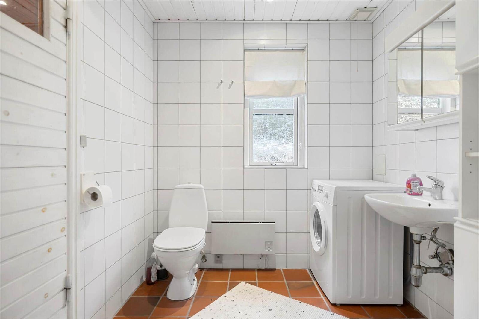 Bathroom with toilet, washing machine, and sink.