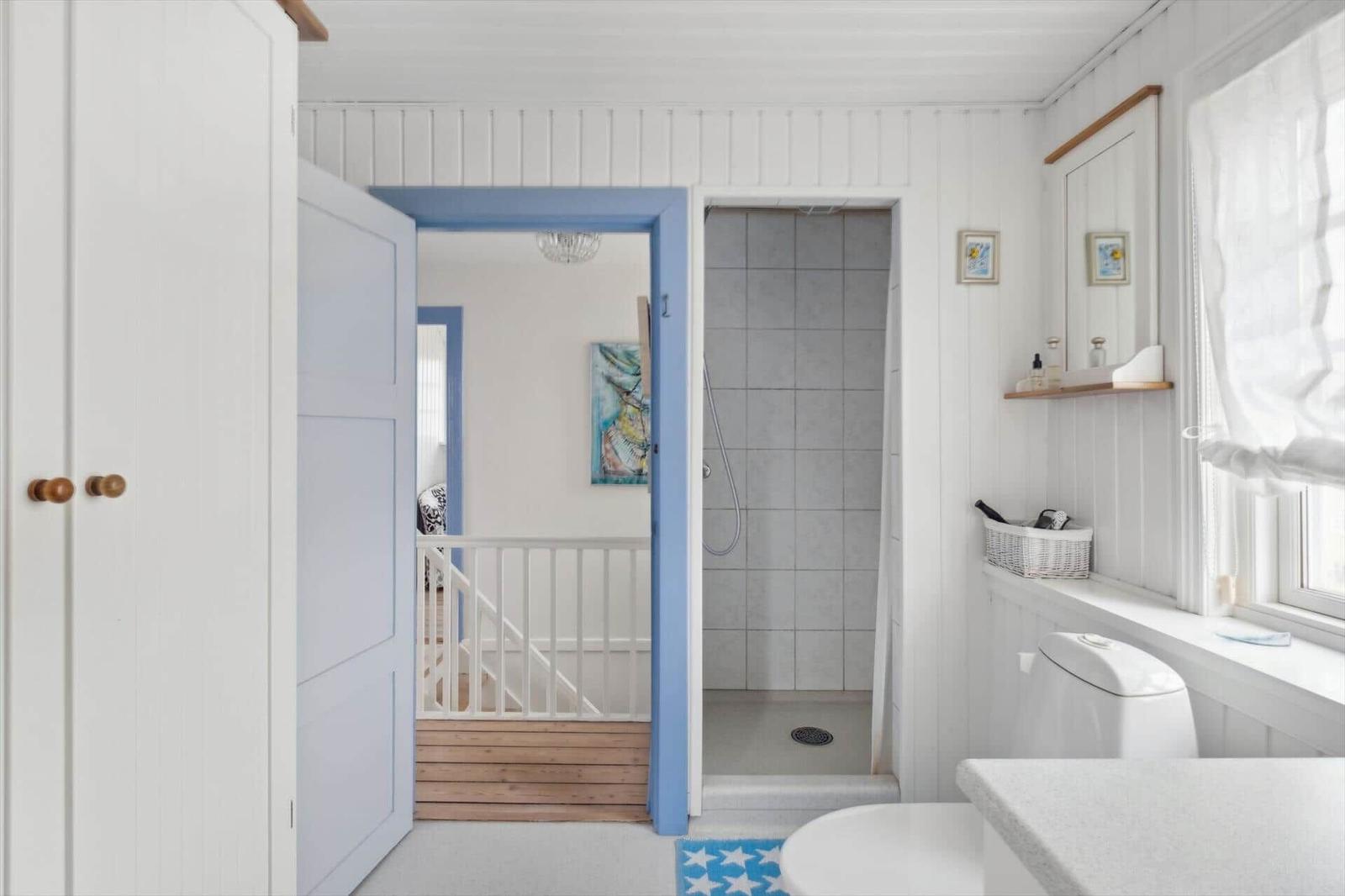 Bathroom with shower, toilet, and window. Door leads to living area.