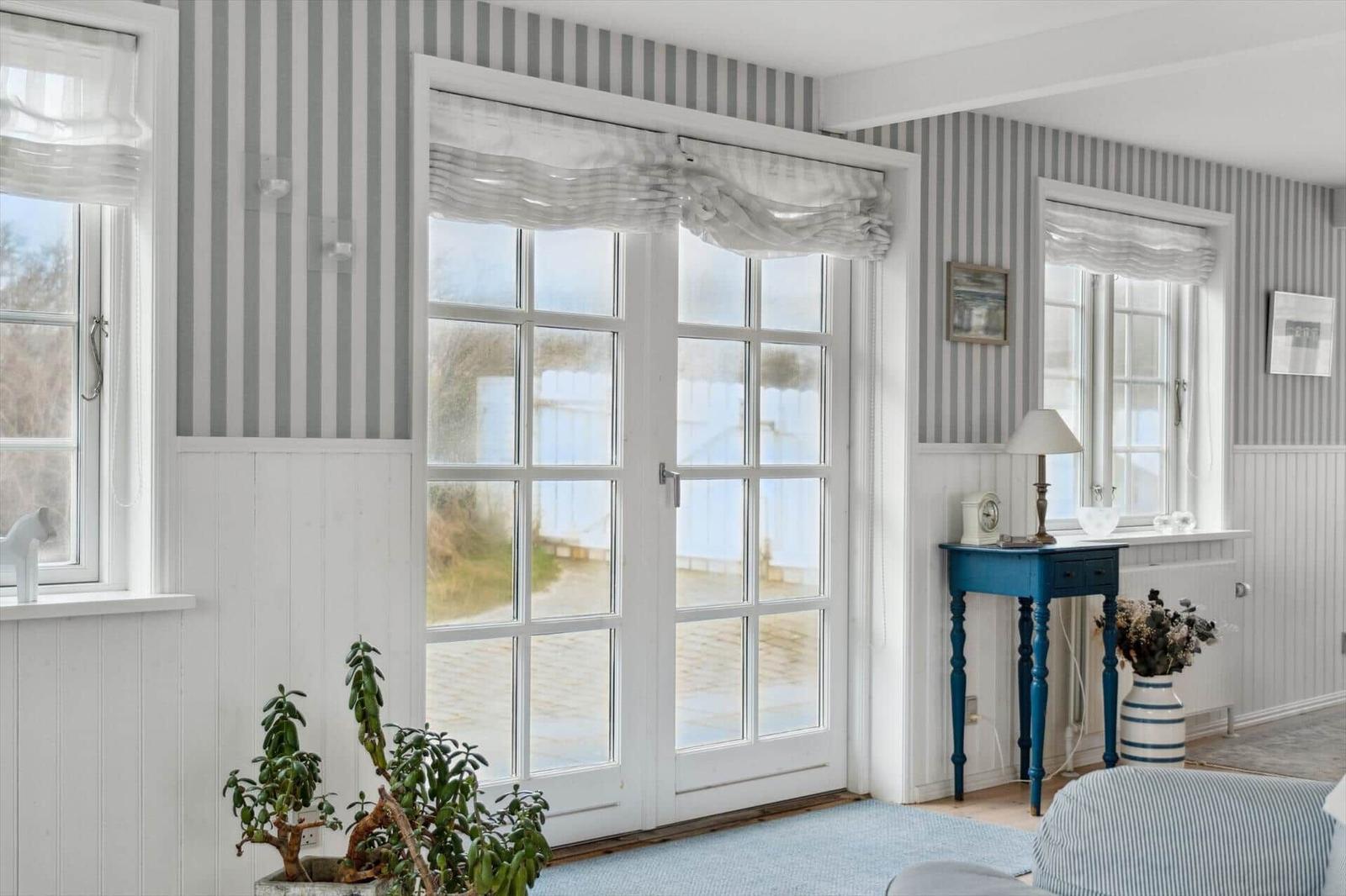 Room with striped wallpaper, white windows, and blue table.
