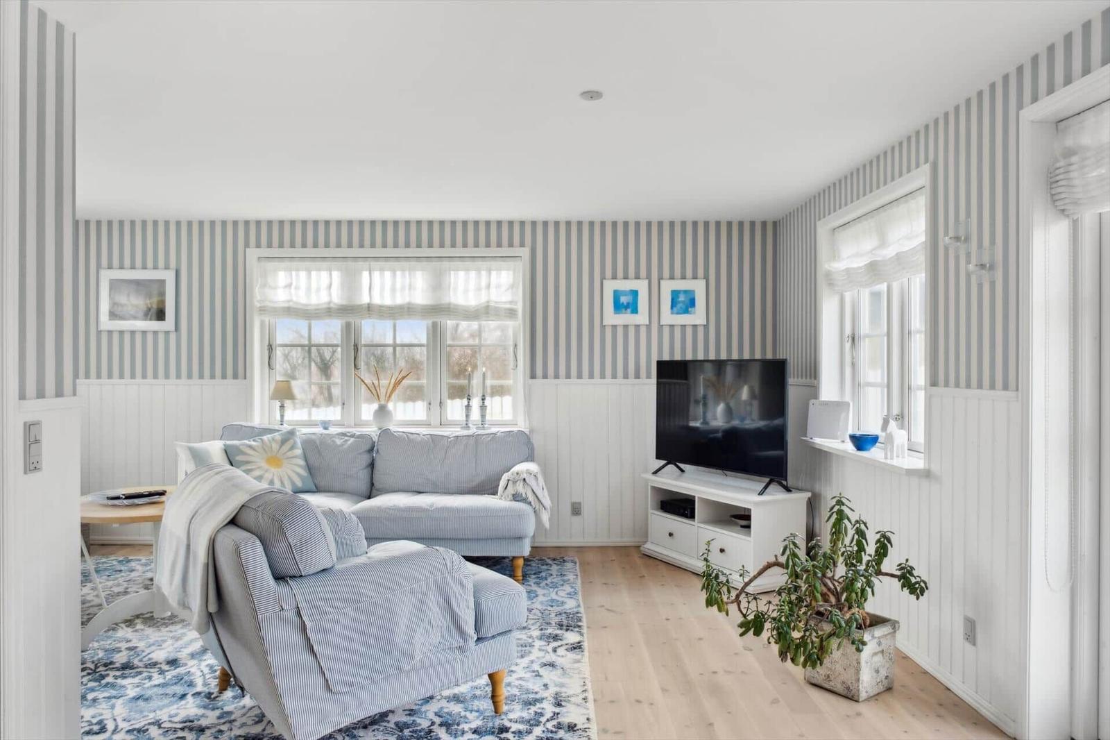 Living room with sofa, TV, and windows.