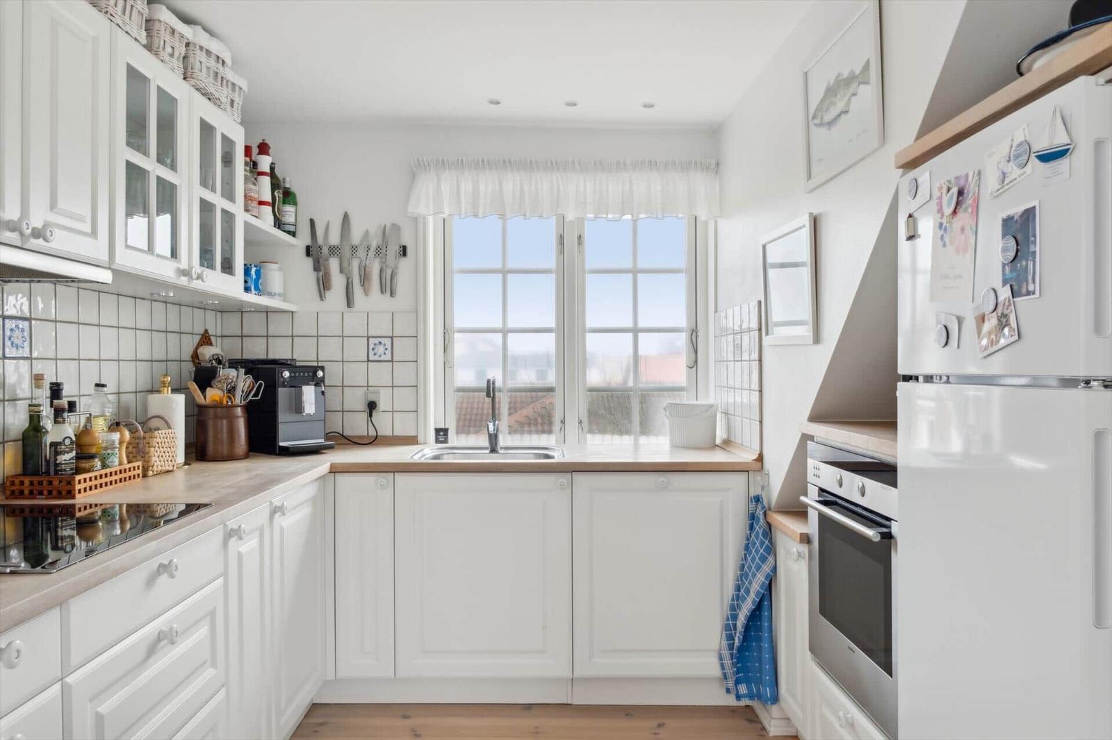 Kitchen with white cabinets, window, and kitchen appliances.
