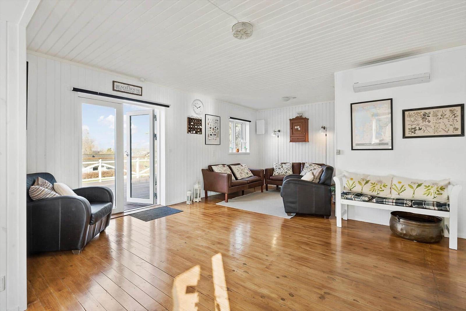 Living space with hardwood floor, white walls, and seating. Entry to outdoor terrace.