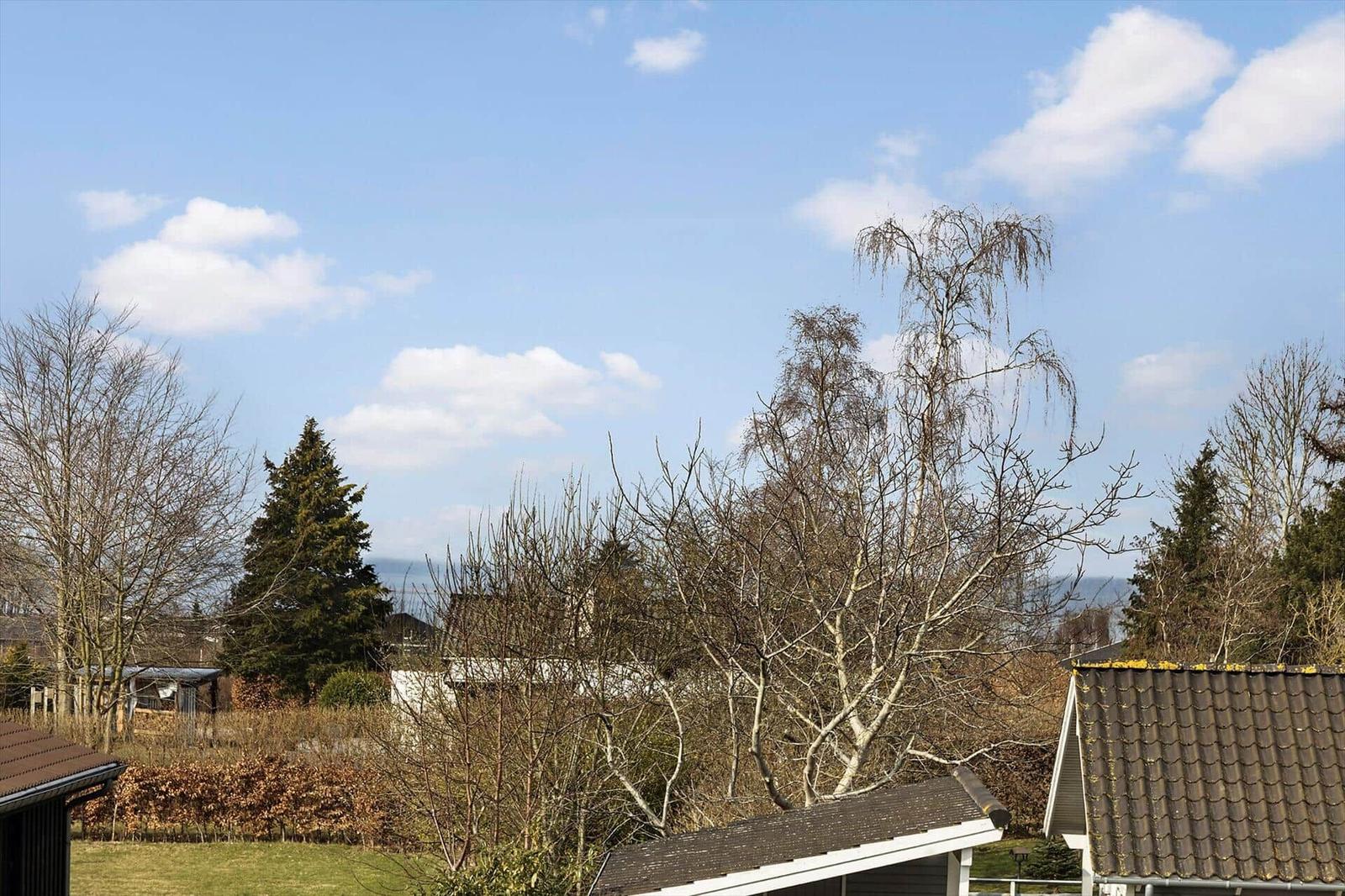 House with view of forest and sky with clouds.