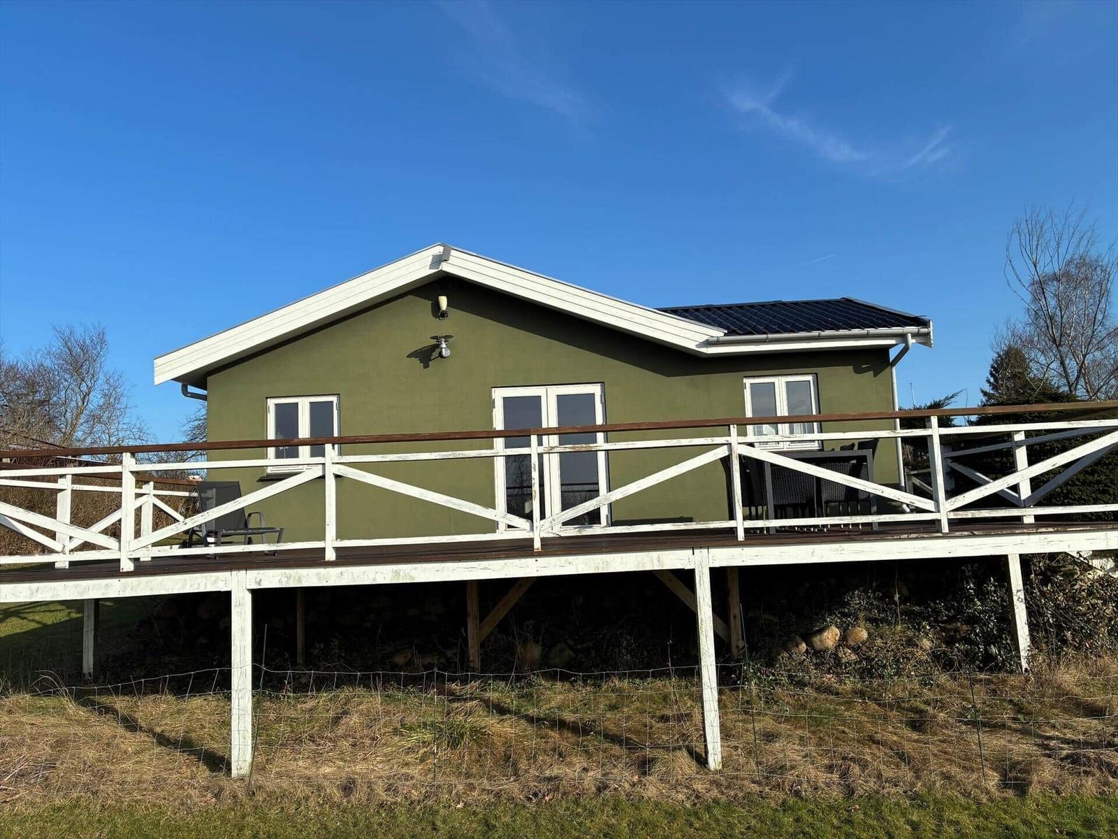 Green house with terrace and garden under blue sky