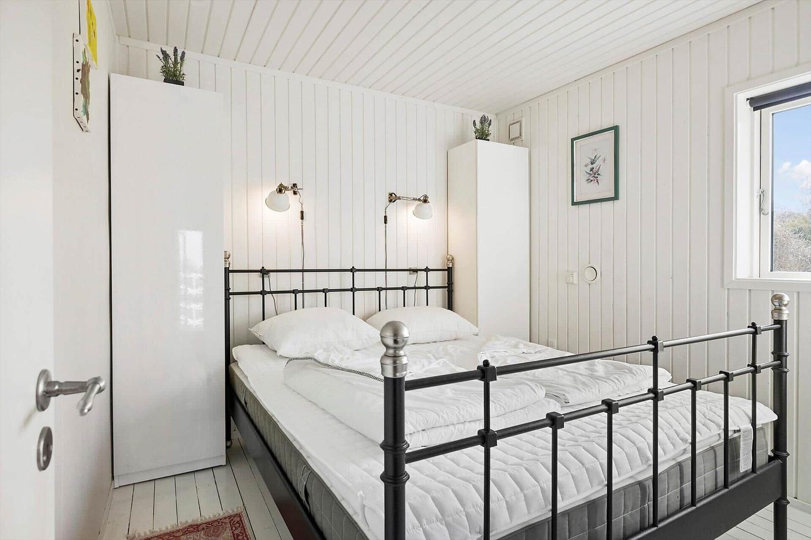 Bedroom with metal bed, white walls, and window.