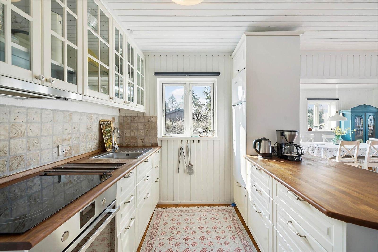 Kitchen with white cabinets, wooden surfaces, and window view of outdoor area.