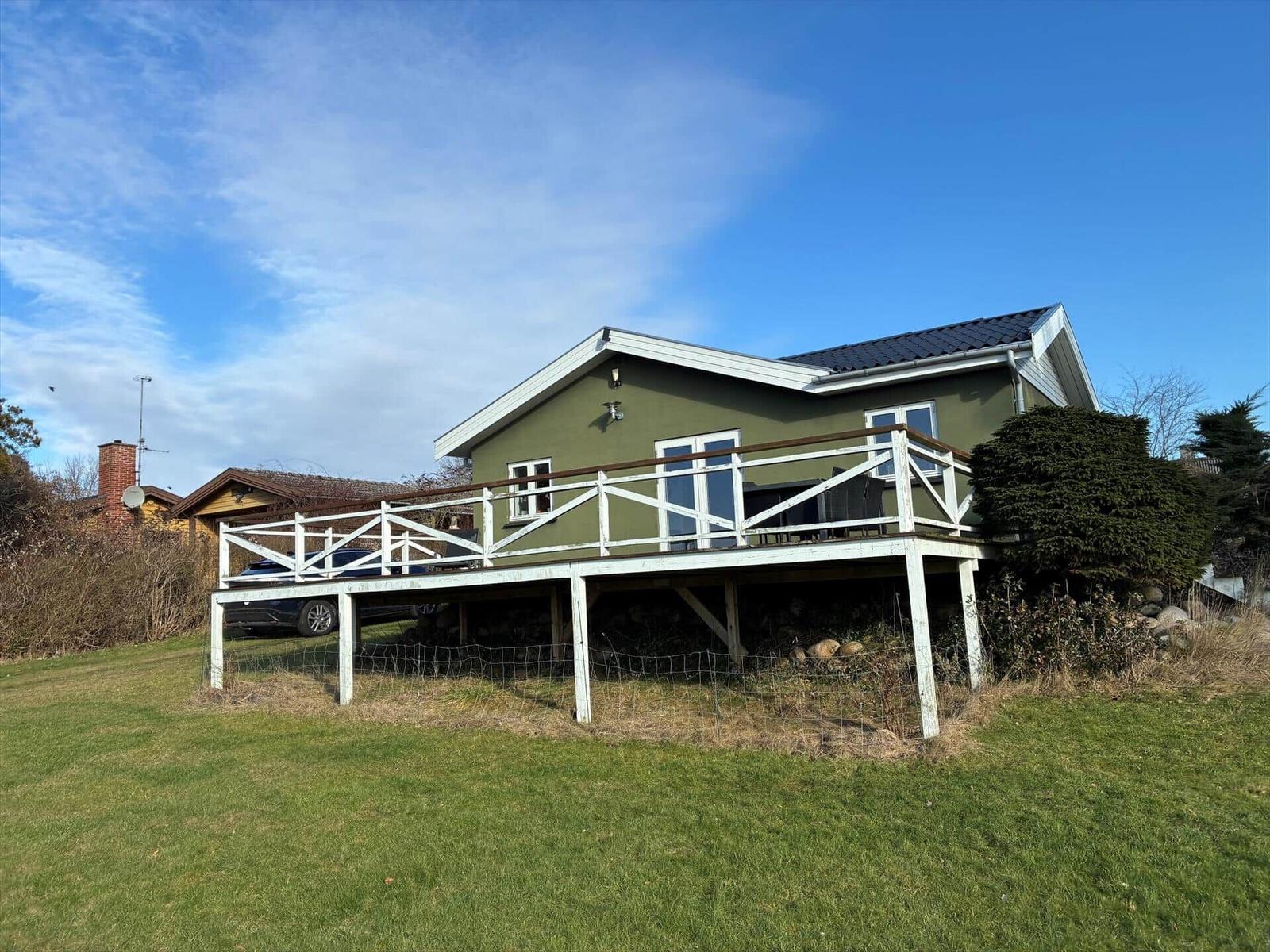 Green house with terrace and garden under blue sky
