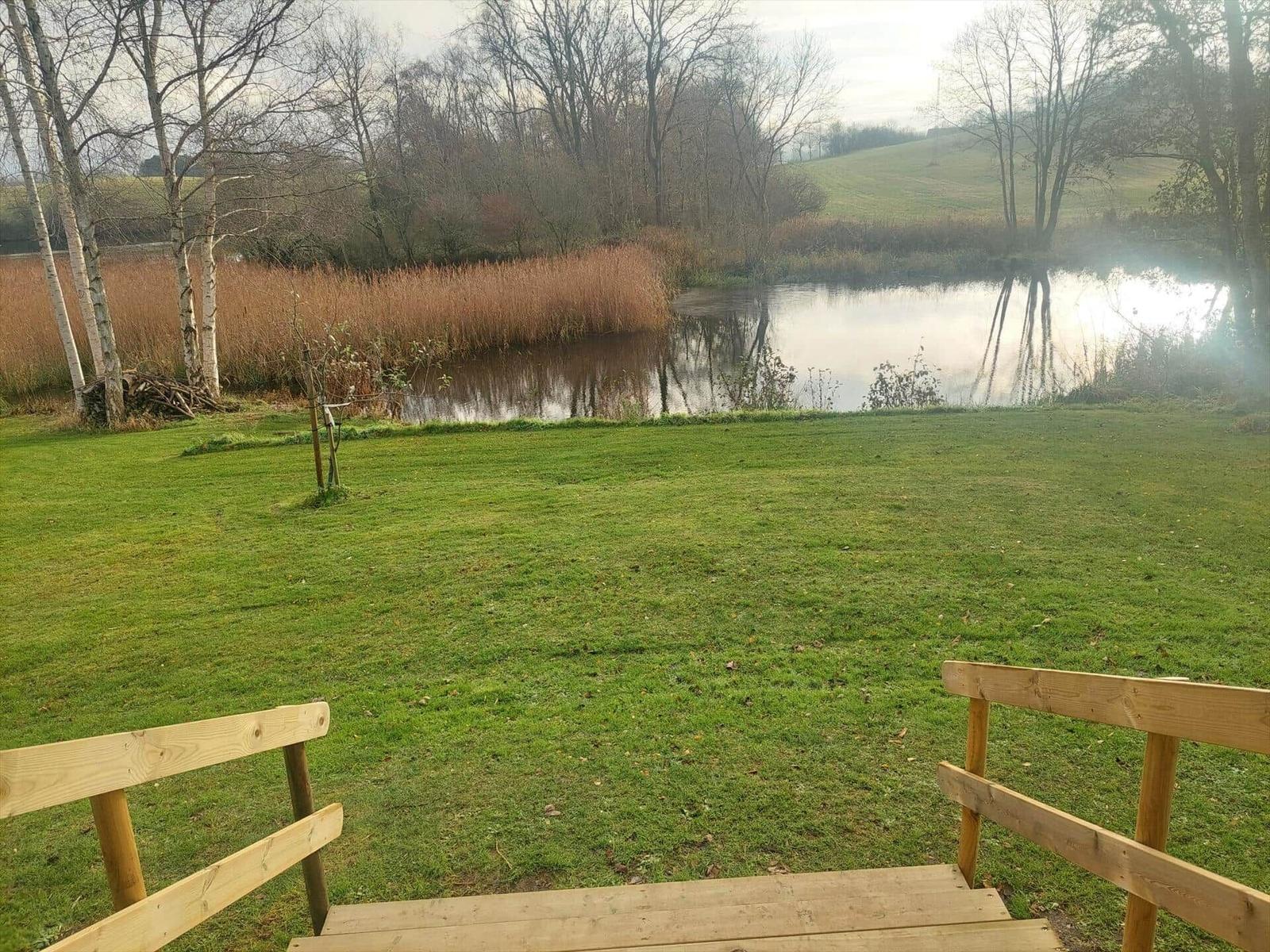 Holzterrasse mit Blick auf einen Teich und Grünfläche