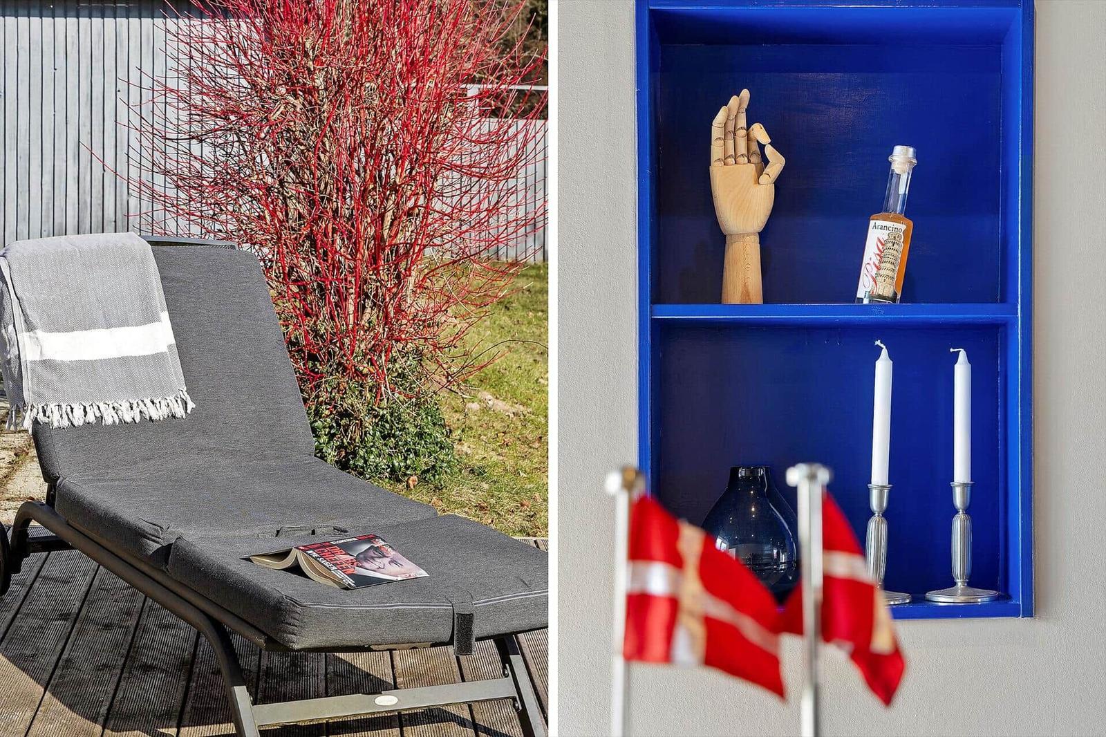 Außenliegende Liege mit Decke und Buch. Innerecke mit blauem Regal, Handmodell, Flasche und Flaggen.