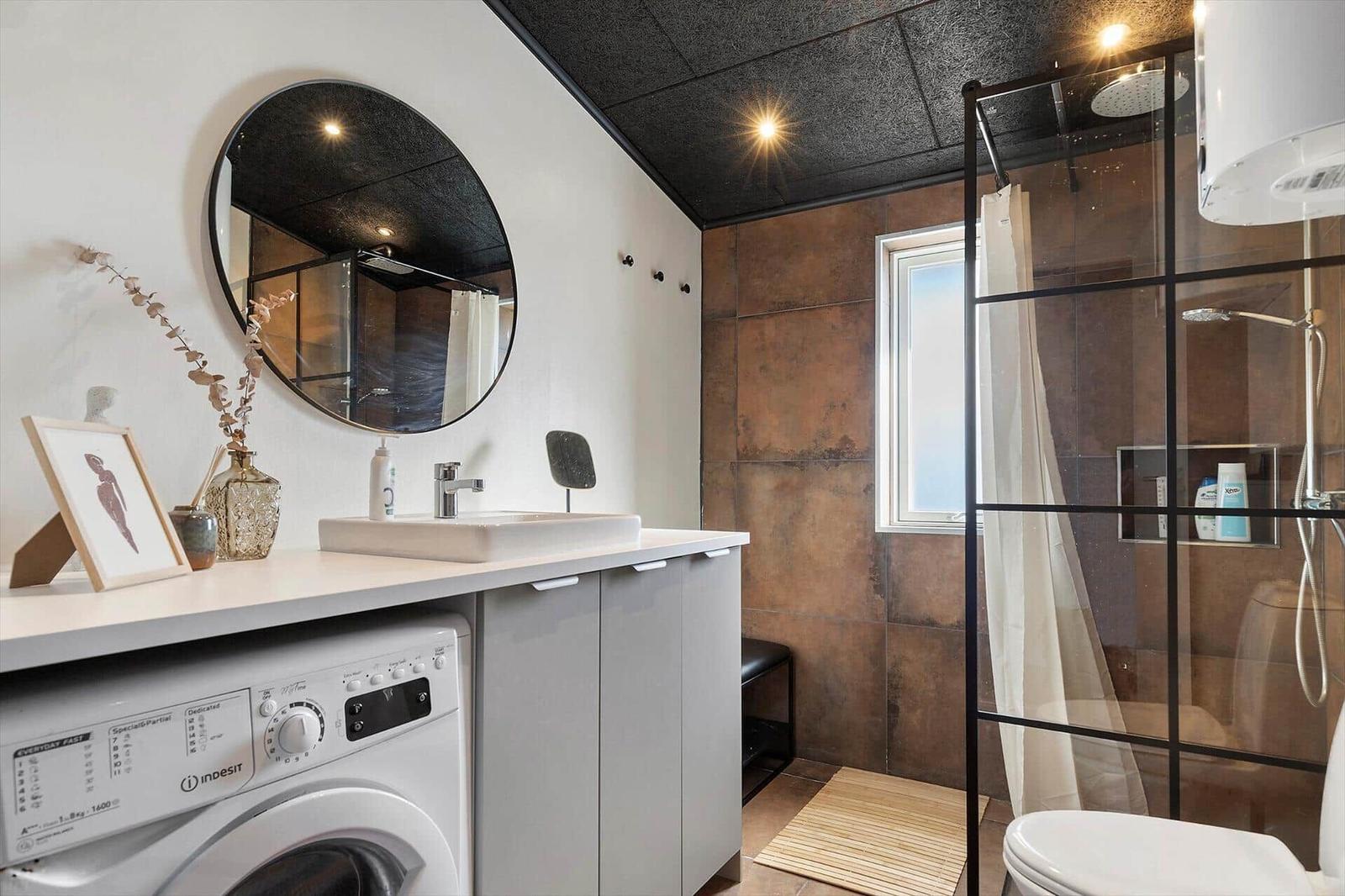 Badezimmer mit Dusche, Waschmaschine und Spiegelschrank.