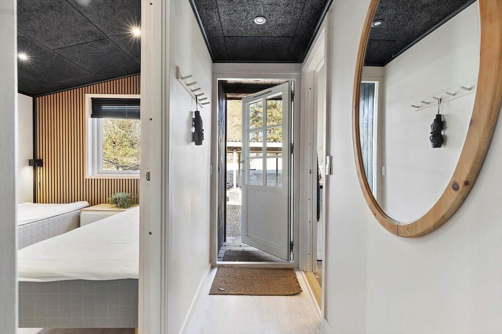 Flur mit Spiegel, Tür zum Hof und Blick in Schlafzimmer mit Bett und Fenster.