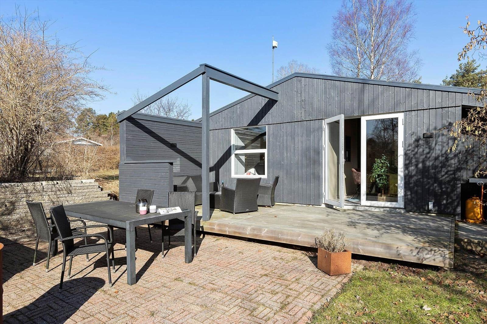 Moderne Holzhütte mit Terrasse und Sitzgelegenheiten im Freien.