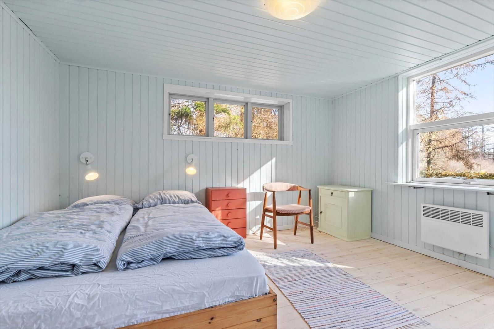 Schlafzimmer mit Doppelbett, Fenstern und Holzboden.