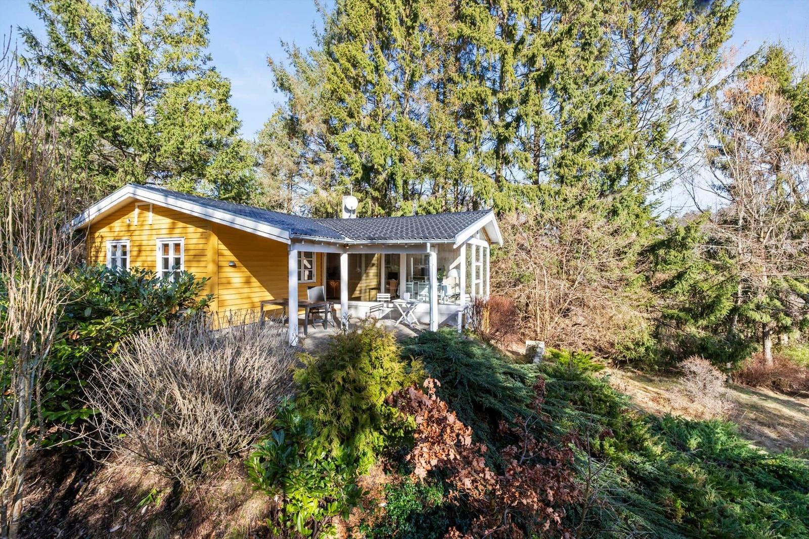 Gelbes Holzhaus mit Terrasse und Garten im Wald