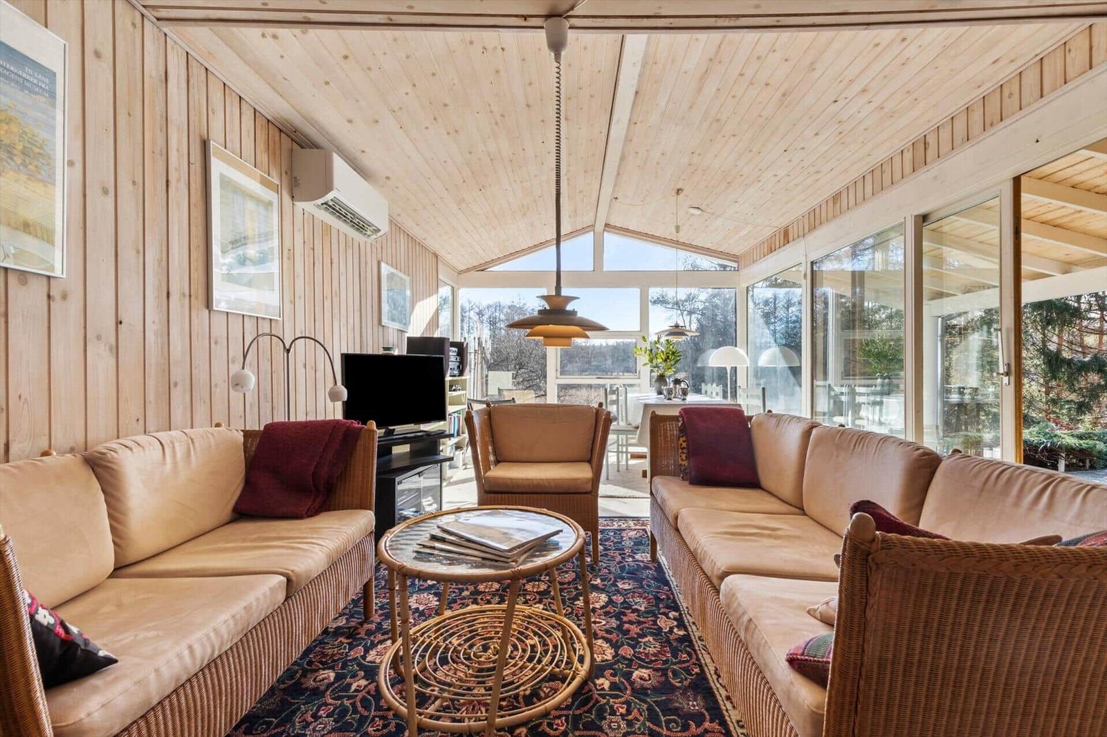 Wohnraum mit Holzwand, Sofa, Tisch und Fenster zur Aussicht.