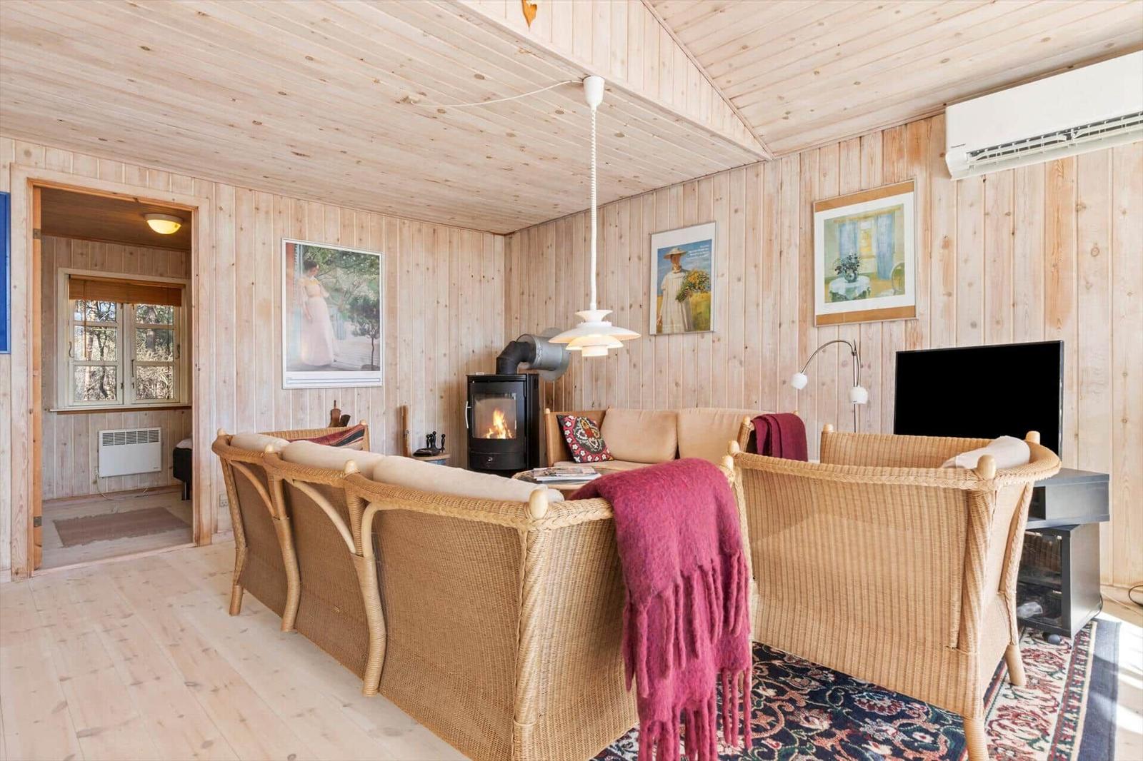 Wohnzimmer mit Holzwand, Kamin und Rattanmöbeln.