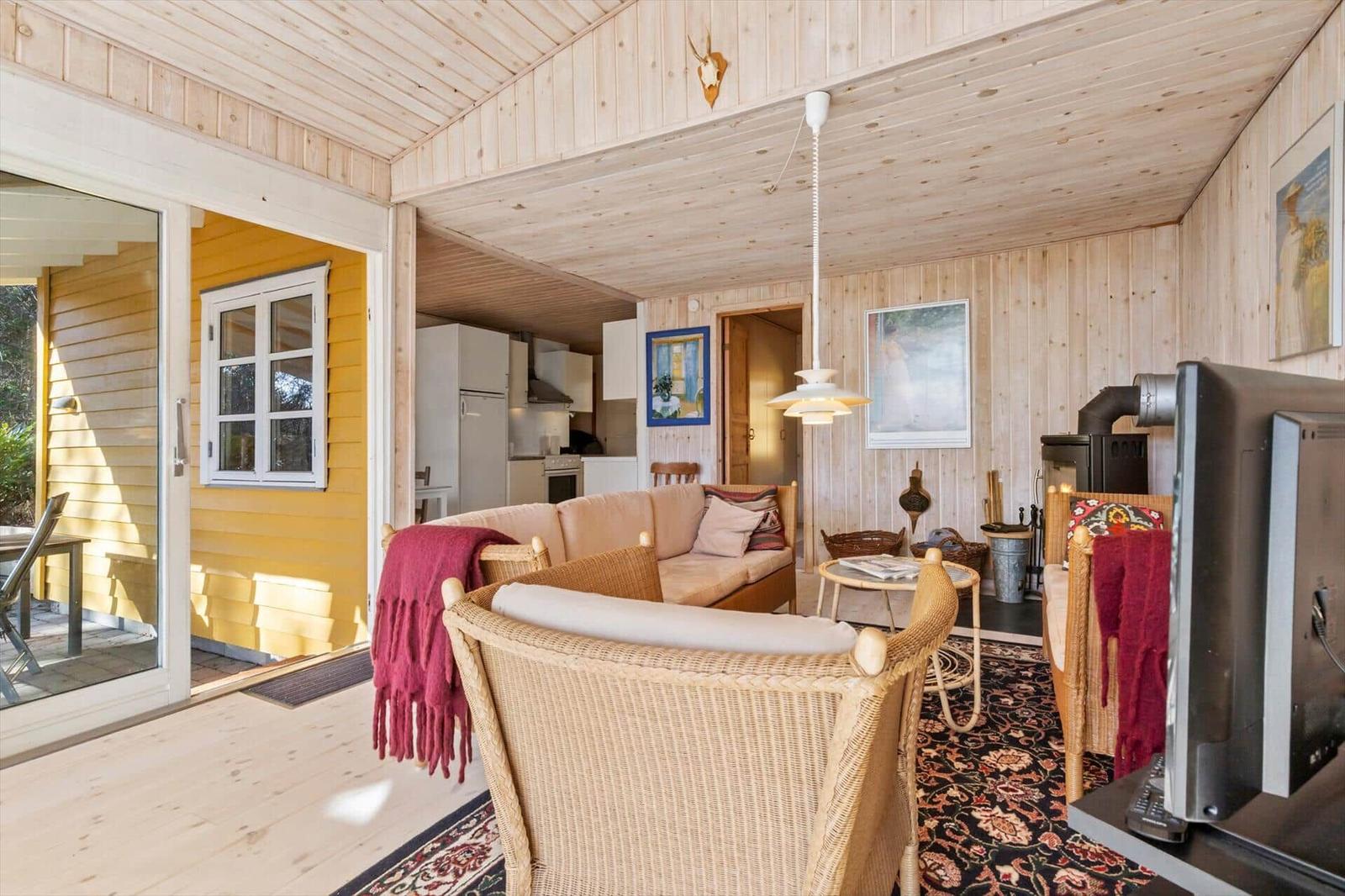 Wohnbereich mit Sofa, Stühlen und Blick auf Küche und Terrasse.