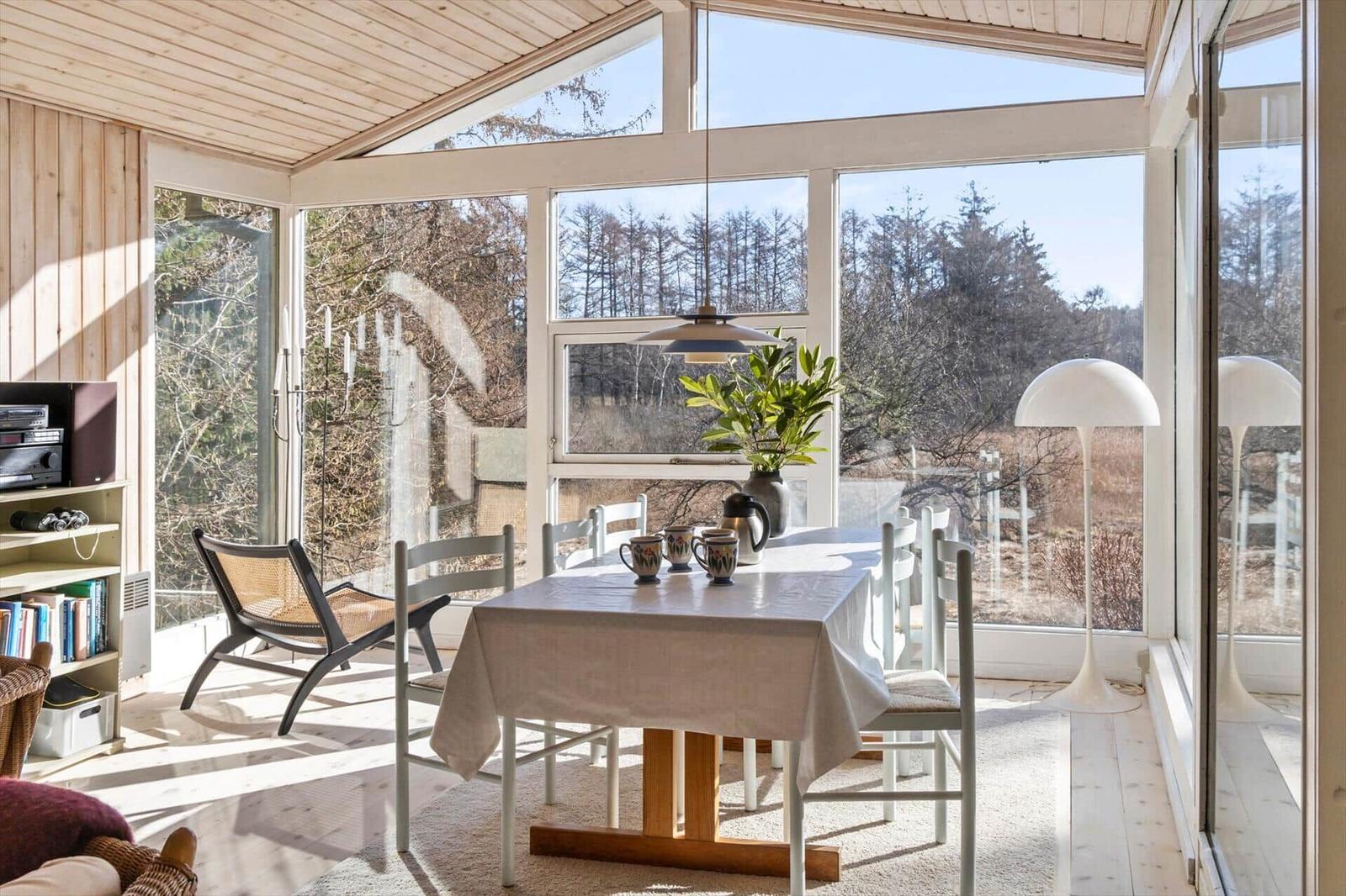 Esszimmer mit Tisch, Stühlen und Blick auf Wald.